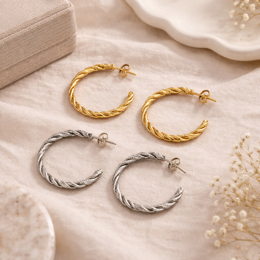 Gold and silver hoop earrings on a soft beige surface with dried flowers.