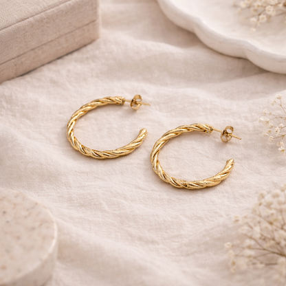Gold hoop earrings on a soft beige surface with a neutral background