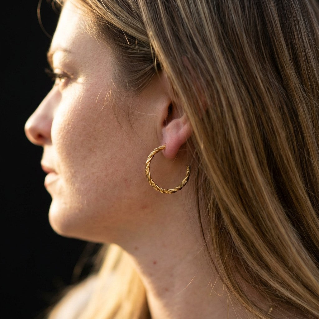 Close-up of a person wearing a gold hoop earring against a dark background