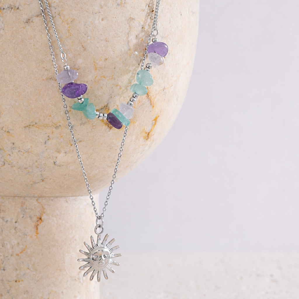 Necklace with sun-shaped pendant and colorful beads on a stone surface