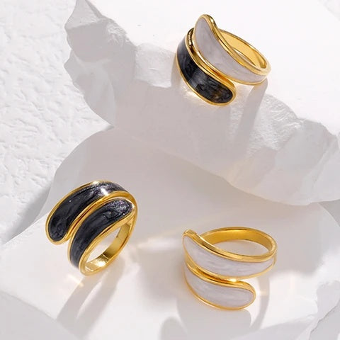 Three tarnish-free gold and black rings on a textured white surface