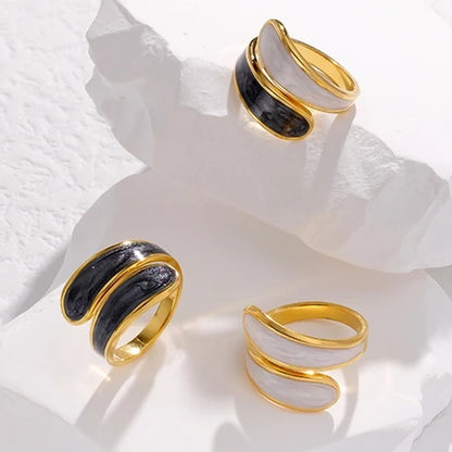 Three tarnish-free gold and black rings on a textured white surface