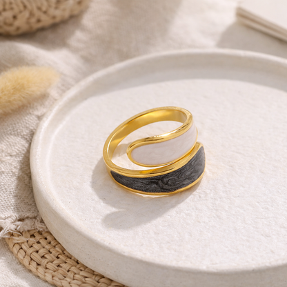 Gold and black stainless steel ring on a white plate with a neutral background