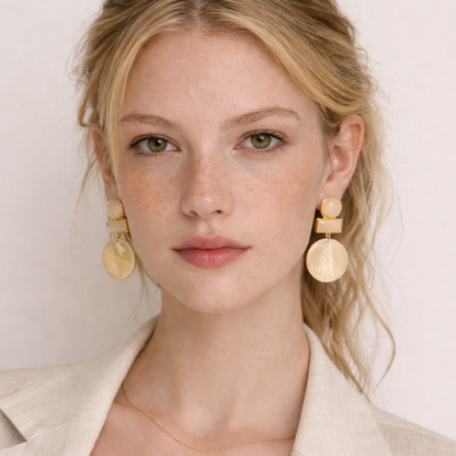 Woman wearing gold statement earrings with a plain background