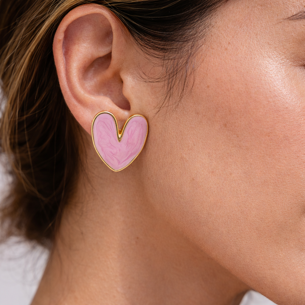 Heart-shaped pink earring worn by a person