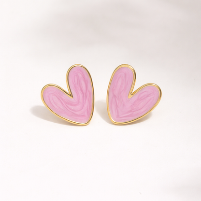 Heart-shaped earrings with pink enamel and gold accents on a white background