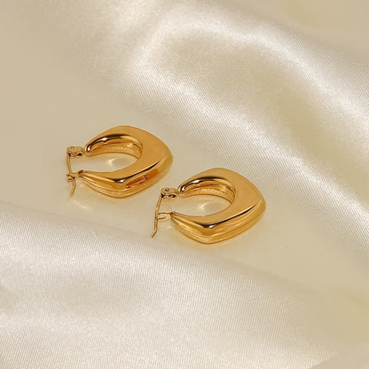 Gold hoop earrings on a satin surface