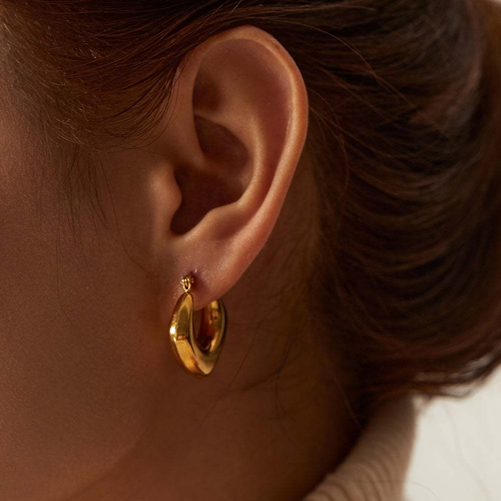 Close-up of a person wearing a gold hoop earring.