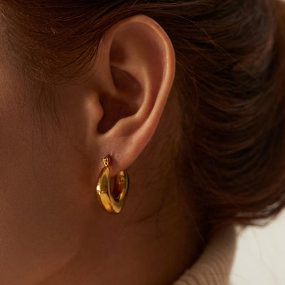 Close-up of a person wearing a gold hoop earring.