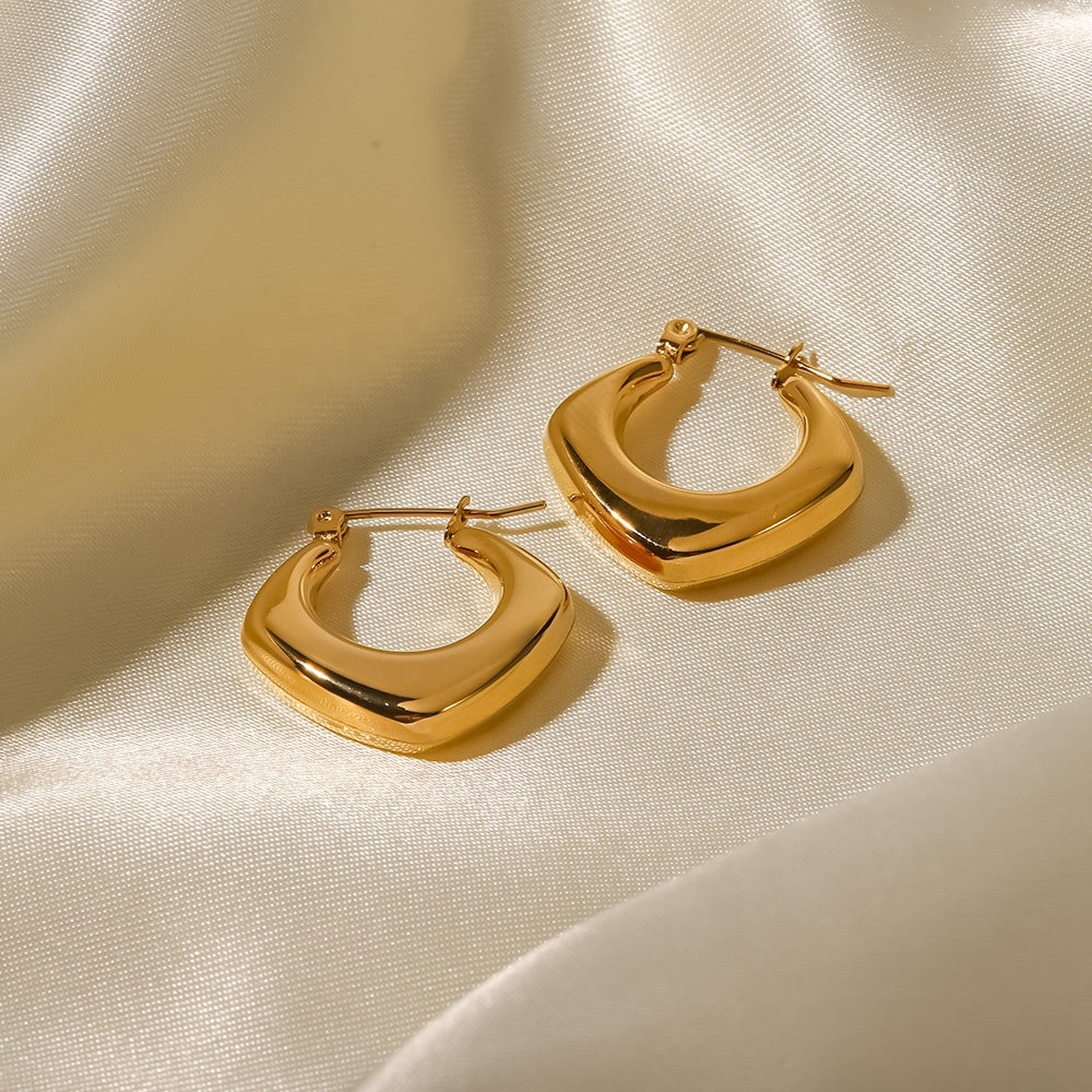 Gold hoop earrings on a beige fabric background