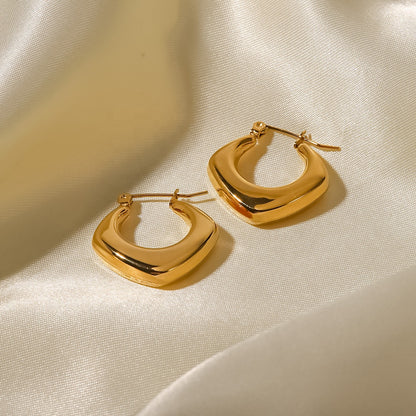 Gold hoop earrings on a beige fabric background