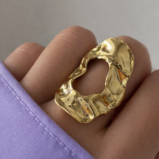 Gold ring on a finger with a plain background