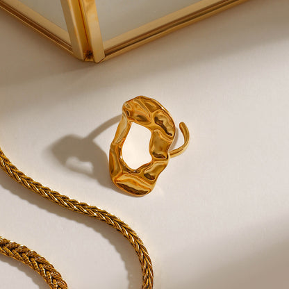 Gold statement ring and necklace on a beige background