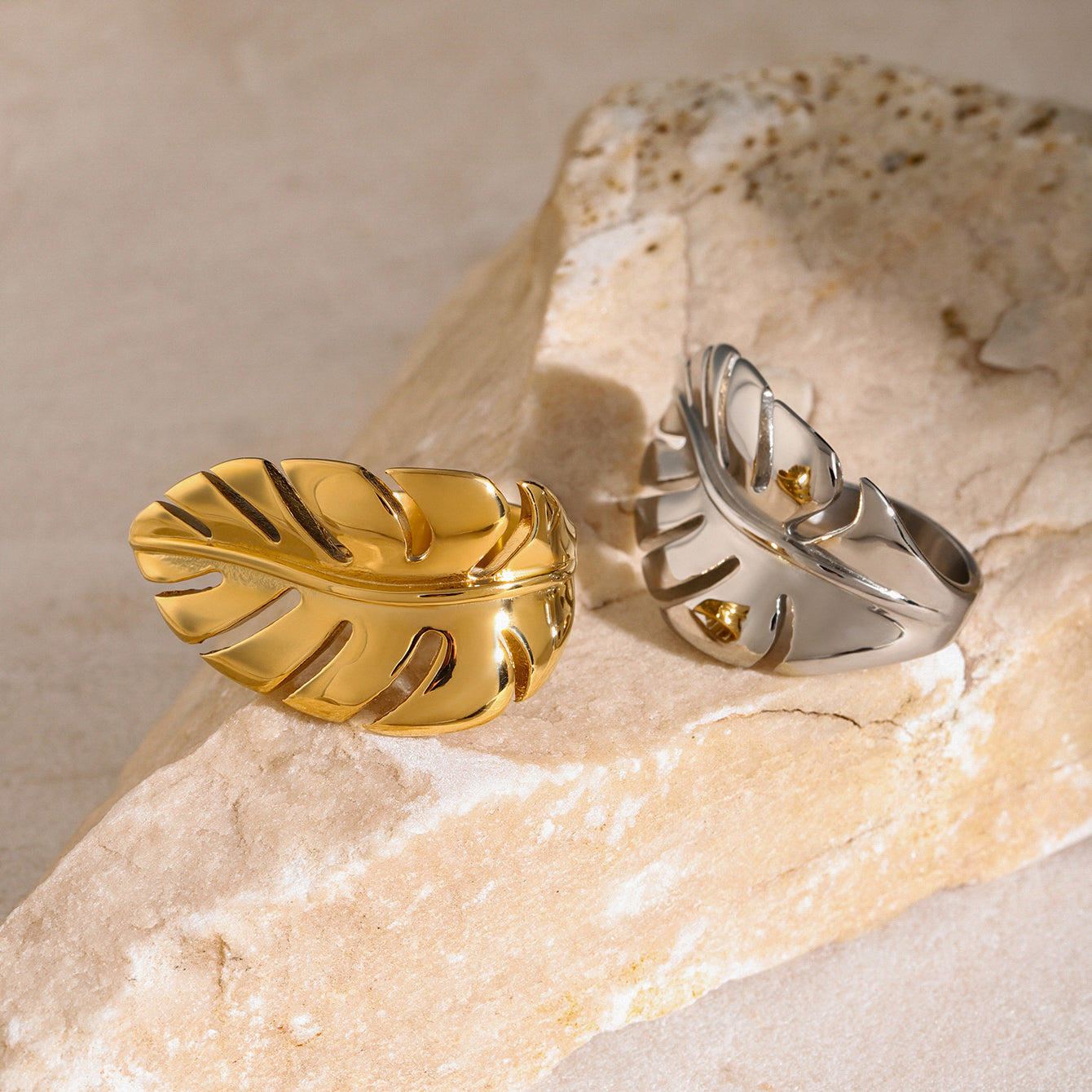Gold and silver leaf-shaped rings on a stone surface