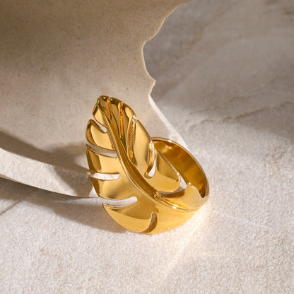 Gold chunky ring with leaf design on a textured beige background