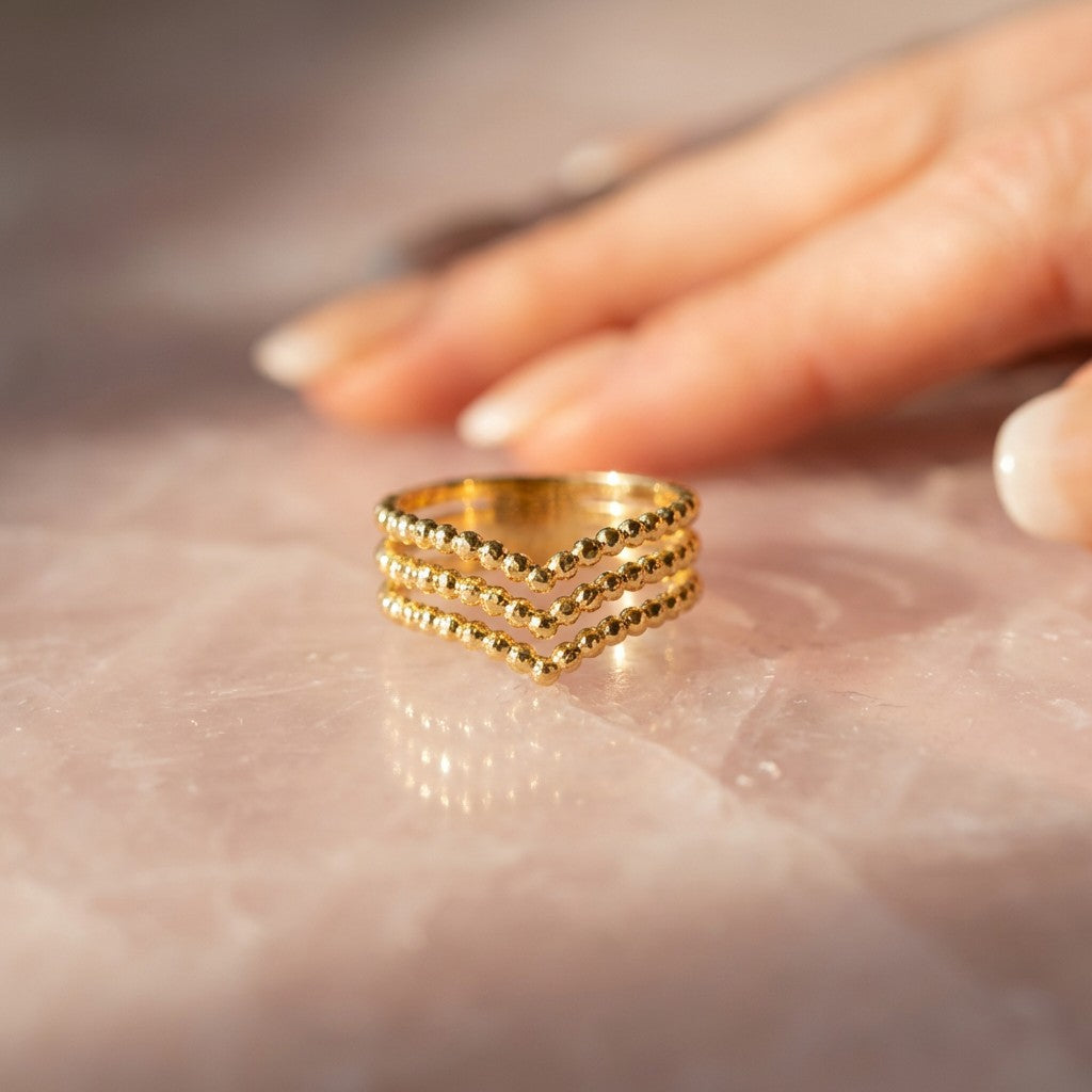 Gold waterproof ring on a marble surface with a hand in the background