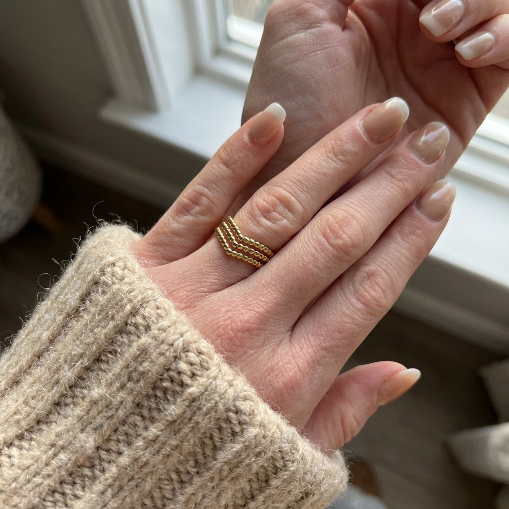 hand wearing a gold beaded ring