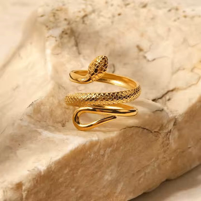 Gold snake-shaped ring on a textured stone surface