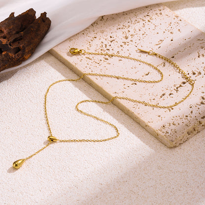 Gold necklace with a pendant on a textured beige surface