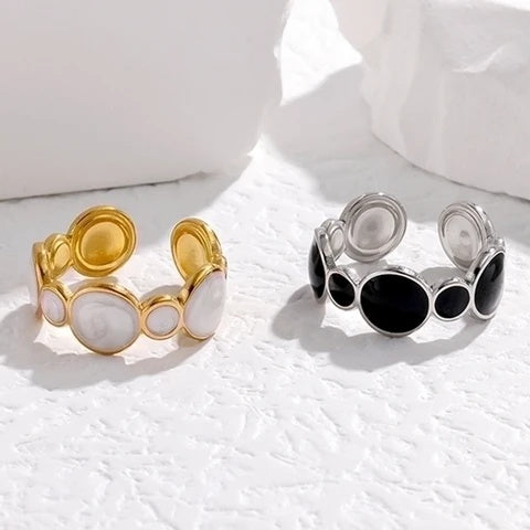 Two tarnish-free rings, one gold and one silver with black accents, on a white surface.