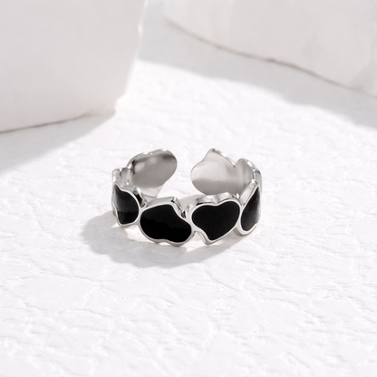 Silver tarnish-free ring with black heart-shaped stones on a white surface