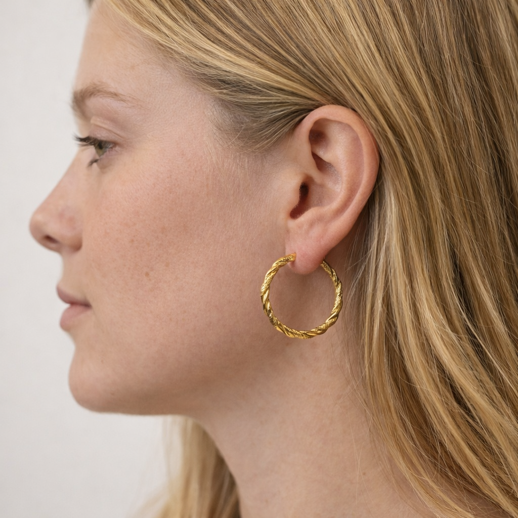 Close-up of a person wearing a gold hoop earring against a neutral background