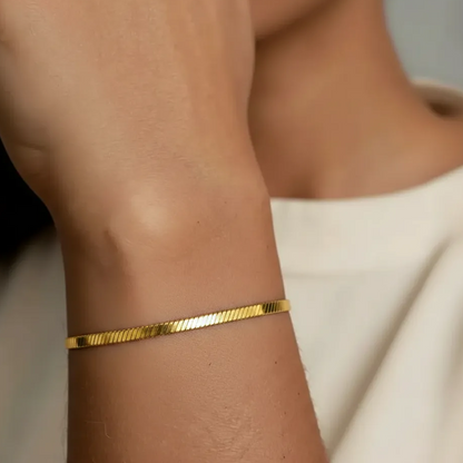 Gold stainless steel  bracelet on a wrist with a neutral background