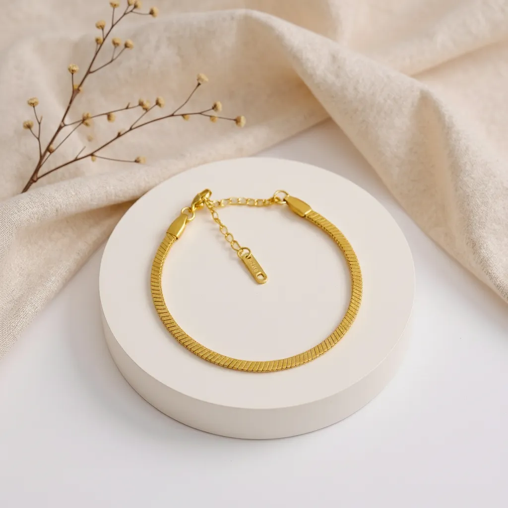 Gold bracelet on a white stand with beige fabric and dried branches in the background
