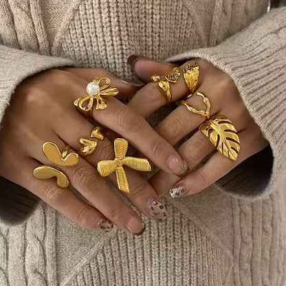 Gold rings on a person's fingers against a beige sweater background