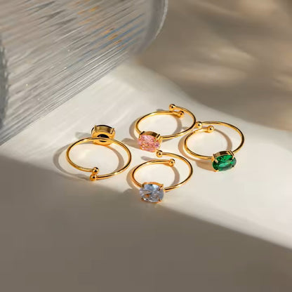 Set of gold rings with colorful gemstones on a light background