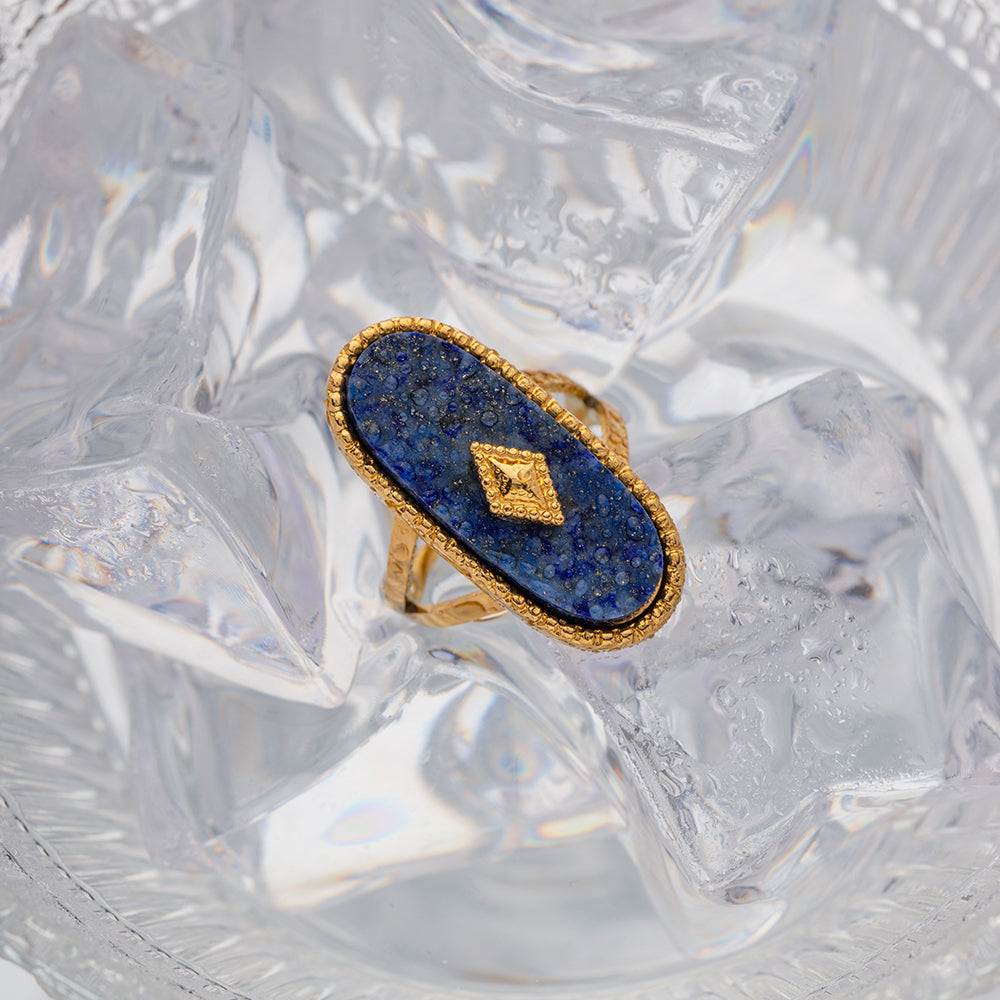 Gold ring with blue stone on a textured white background