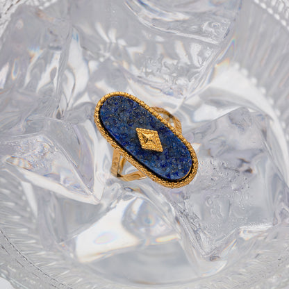 Gold ring with blue stone on a textured white background