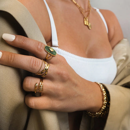 Close-up of a hand wearing gold rings and bracelets with a neutral background