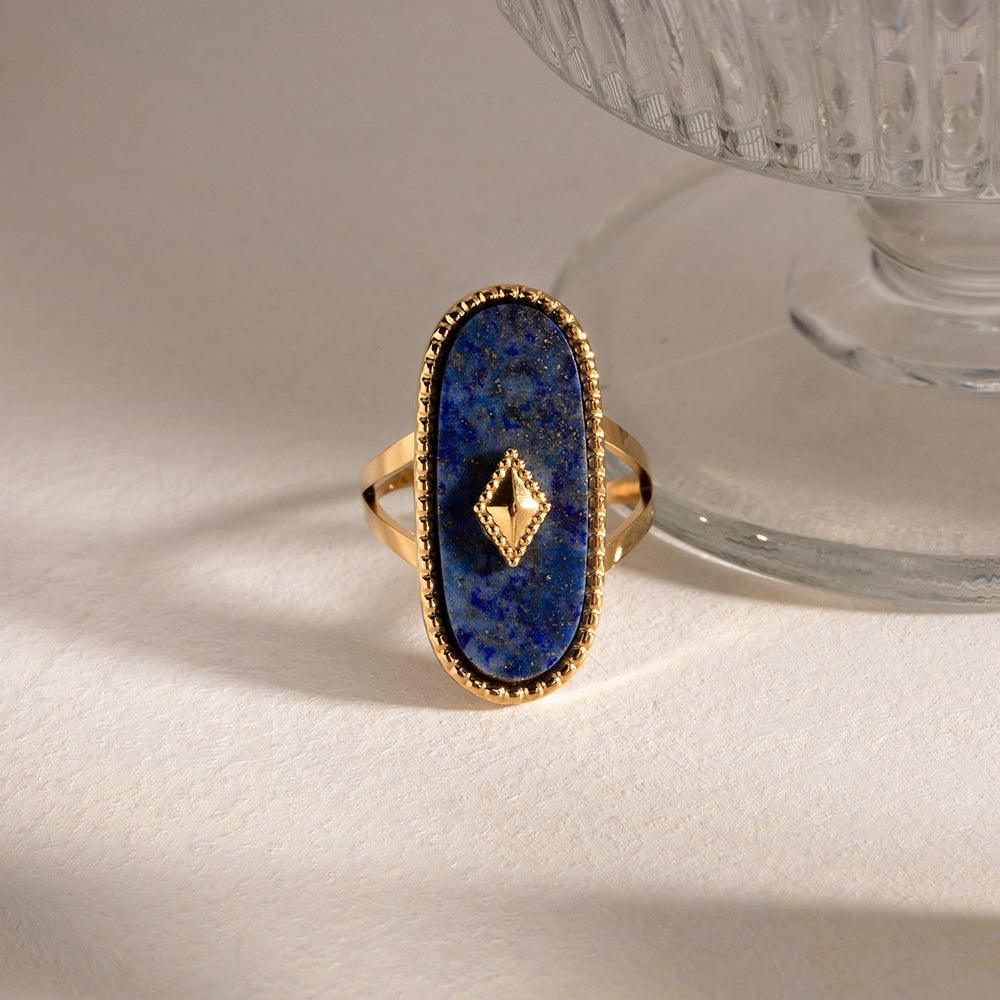 Gold statement ring with a blue stone on a white surface