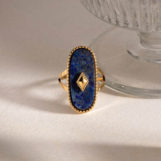 Gold statement ring with a blue stone on a white surface