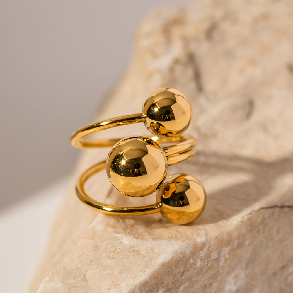 Gold statement ring with spherical designs on a stone surface