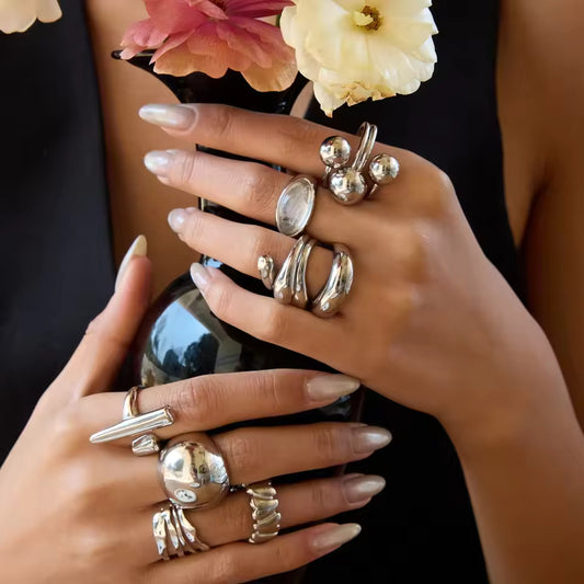 Close-up of hands wearing multiple silver statement rings with a blurred background
