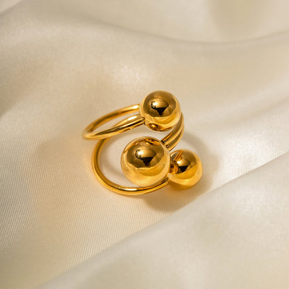 Gold stainless steel ring with spherical design on a beige fabric background