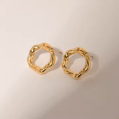Pair of gold stainless steel hoop earrings on a beige background