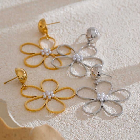 Pair of gold and silver flower-shaped earrings on a textured surface