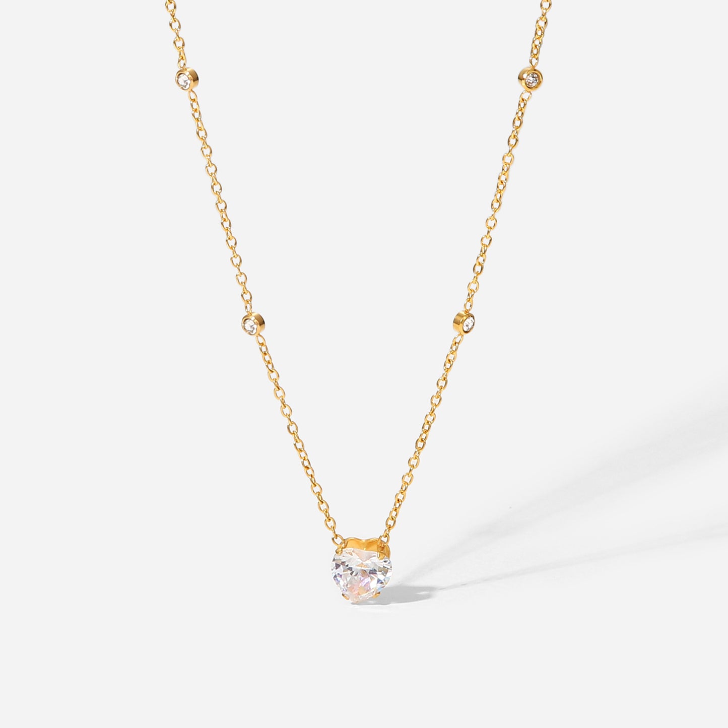 Gold necklace with a clear gemstone pendant on a white background