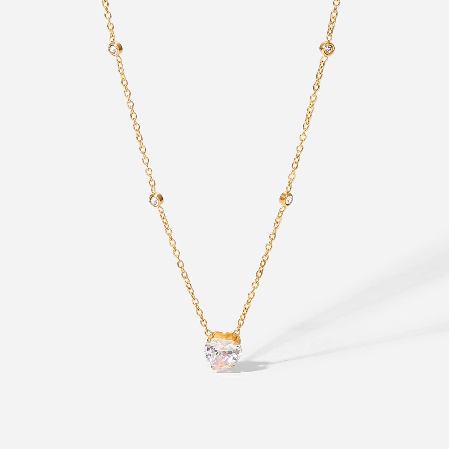 Gold necklace with a clear gemstone pendant on a white background