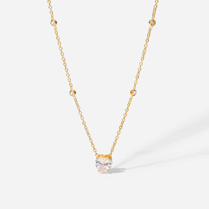 Gold necklace with a clear gemstone pendant on a white background