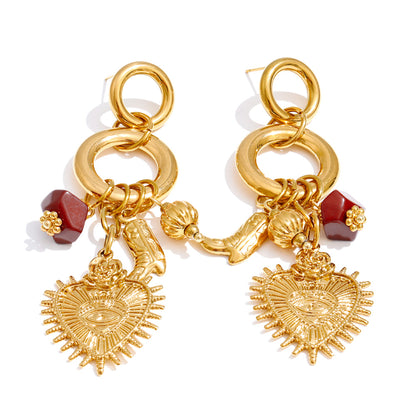 Pair of gold earrings with heart-shaped charms and red beads on a white background