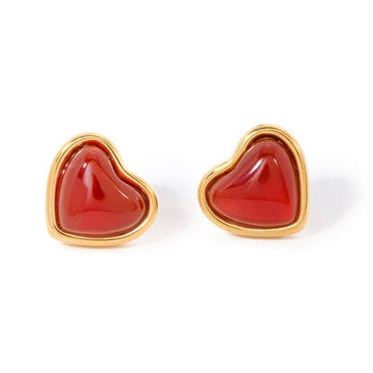 Heart-shaped earrings with red stones and gold frames on a white background