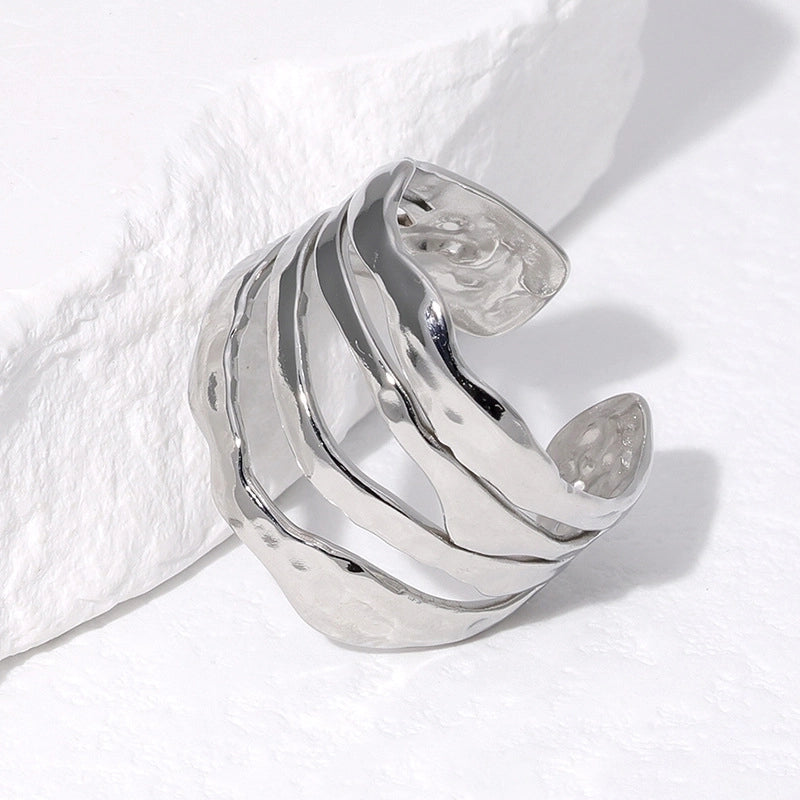 Silver ring with wavy design on a white fabric background