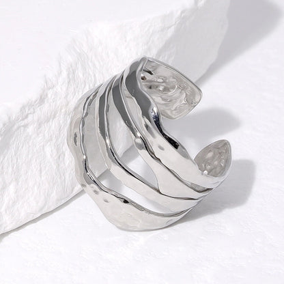 Silver ring with wavy design on a white fabric background