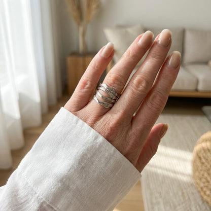 Hand wearing a silver ring with a blurred indoor background