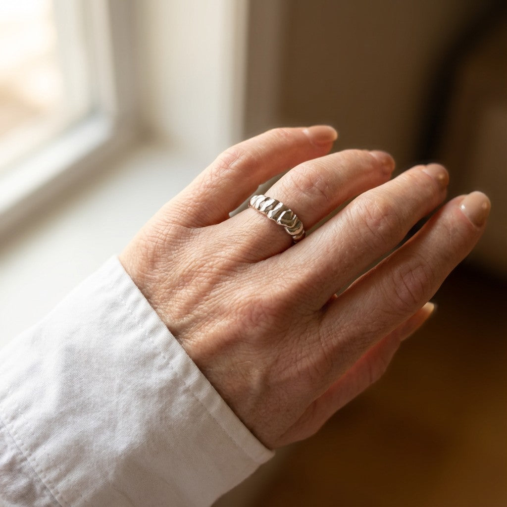 Hand wearing a silver stainless steel ring with a blurred background