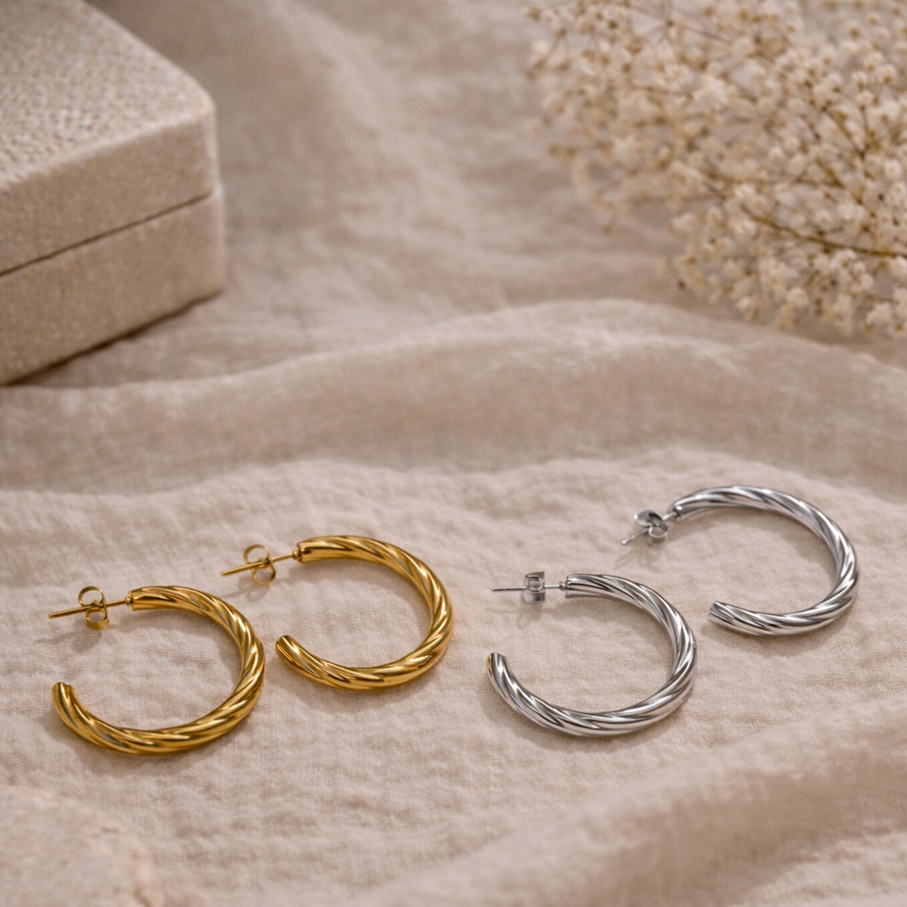 Gold and silver hoop earrings on a soft beige fabric background